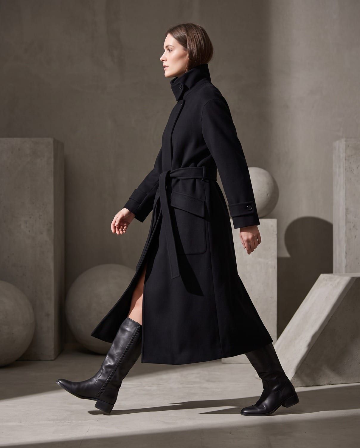 Una donna con un cappotto lungo nero con cintura